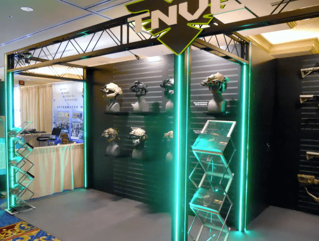 Why Your Company Needs a Branded Showroom Exhibit Studios Custom Booth Services A showroom uses graphics and neon lighting to display tactical gear.