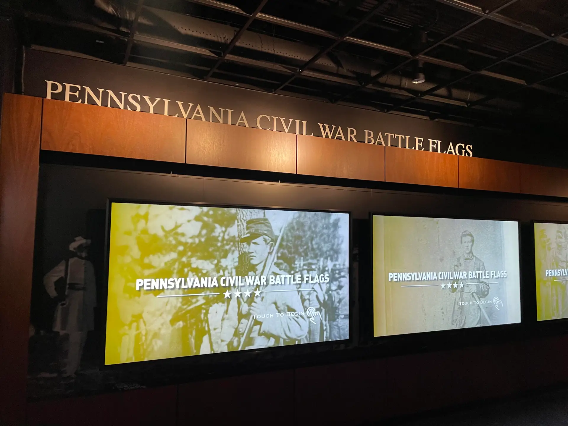 Honoring History: Exhibit Studios' Remarkable Civil War Battle Flag Exhibit Exhibit Studios Image of three planar touch screens that are 98in. All mounted inside splay cases with black sounding and natural wood laminate outer trim.