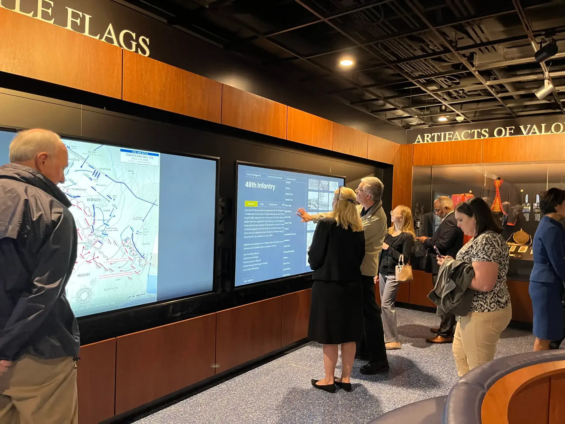 Honoring History: Exhibit Studios' Remarkable Civil War Battle Flag Exhibit Exhibit Studios visitors using touch screens that ar e98in and mounted inside display case. Large die cut letters in stainless steel above display case.