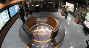 Honoring History: Exhibit Studios' Remarkable Civil War Battle Flag Exhibit Exhibit Studios overhead fisheye lens shot of museum floor showing large printed floor decal and custom round benches with blue leather upholstery