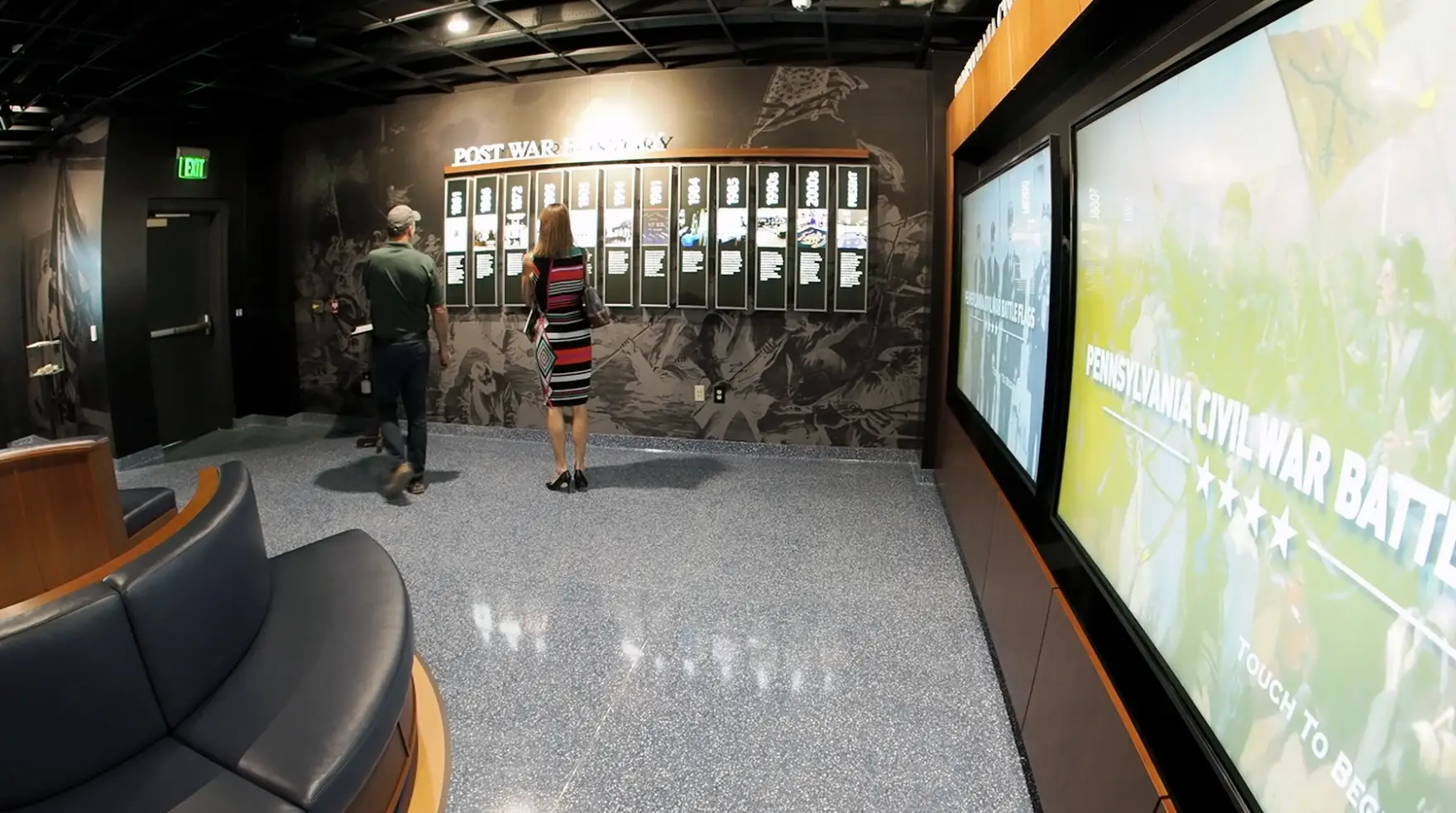 Honoring History: Exhibit Studios' Remarkable Civil War Battle Flag Exhibit Exhibit Studios Wide angle shot with fisheye lens showing touch screen to extreme right and time line wall center with onlookers. Round seating benching in the left with blue leather upholstery