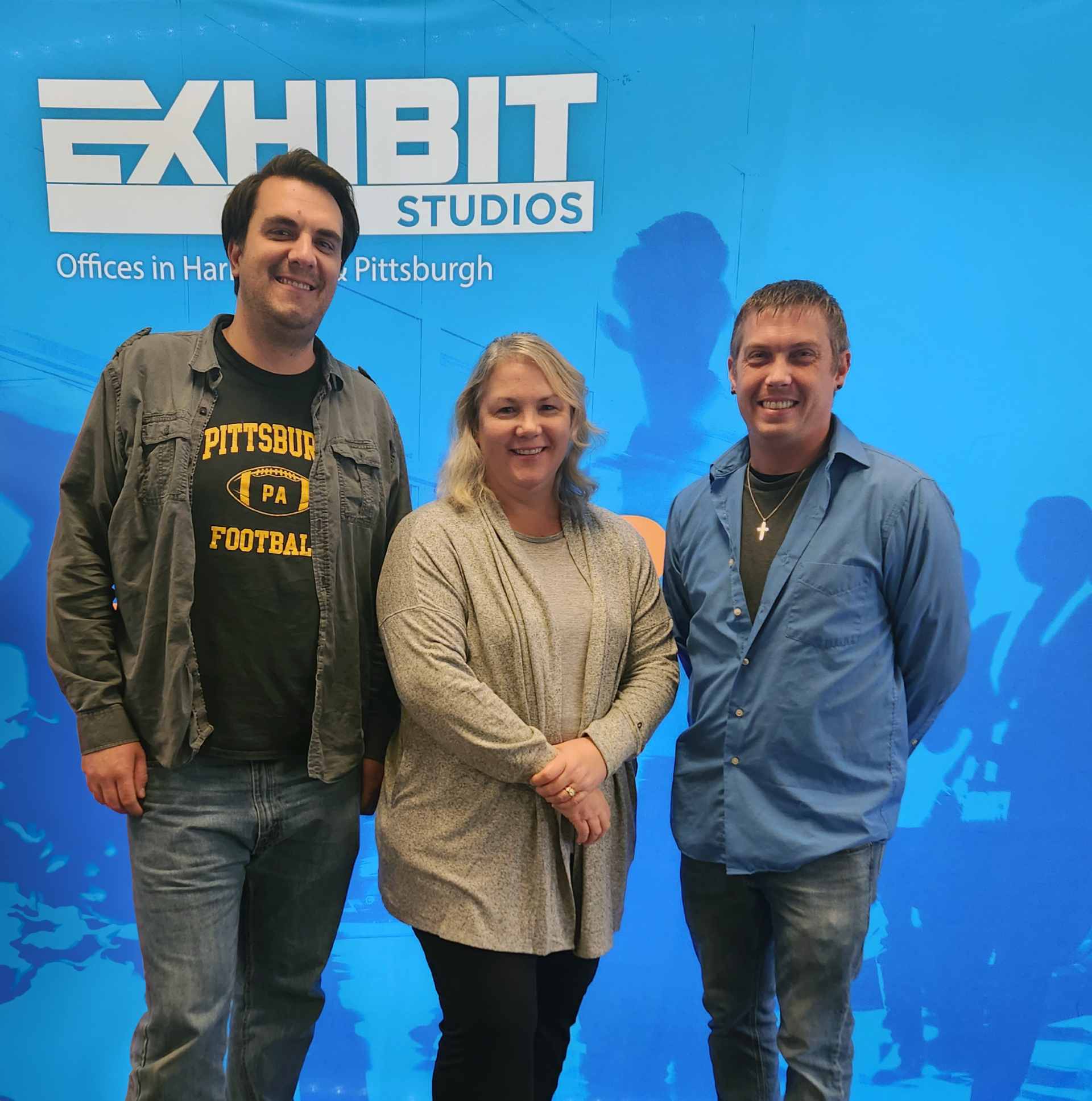 employees posting in front of Exhibit Studios sign