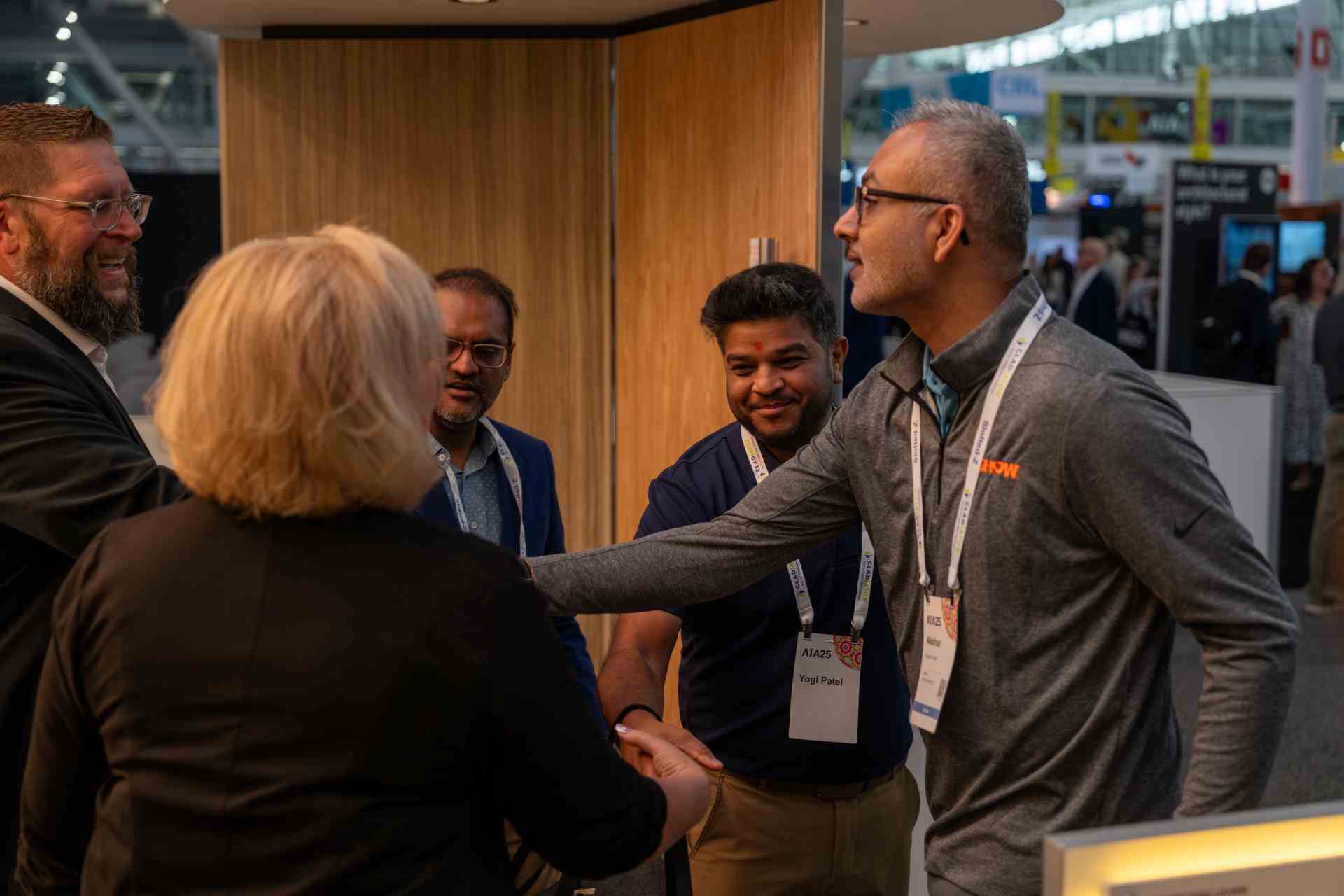 people shaking hands in trade show booth, smarter tech real people